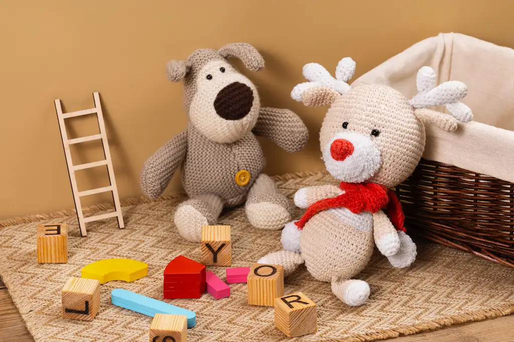 Crocheted bear and reindeer toys with wooden blocks and a basket on a rug