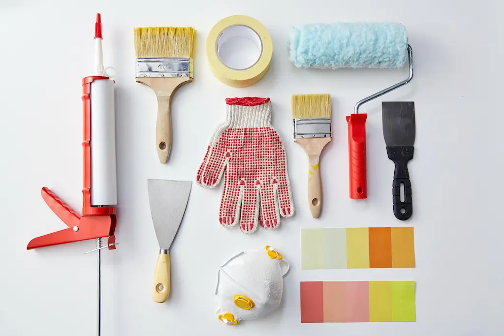 Flat lay of pro painting tools—rollers, brushes, tape, scrapers, and color swatches - Cleanfanatics