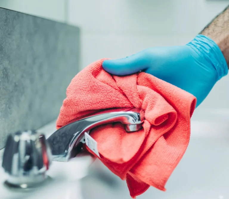 Cleaning a faucet with a red cloth.