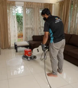Cleaning professional using a single-disc machine to deep clean tiled floors in a living room.