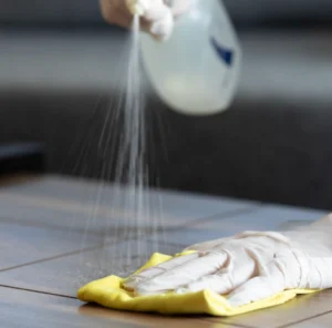 Spray bottle and cleaning cloth on a tiled floor, ready for disinfecting.