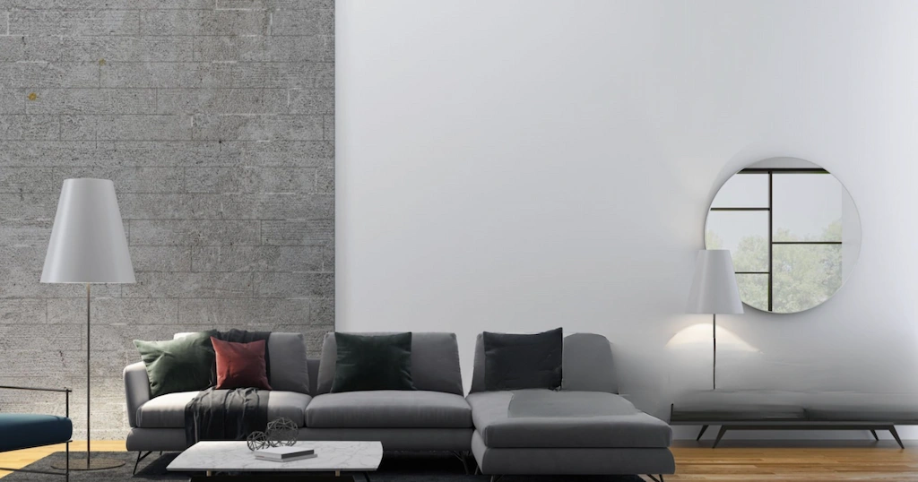 Modern living room with a sectional sofa, gray accent wall, and large round mirror.