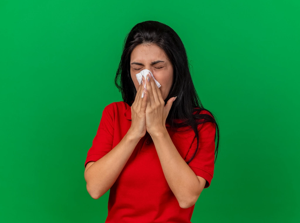 Woman in red shirt covering mouth, showing illness symptoms