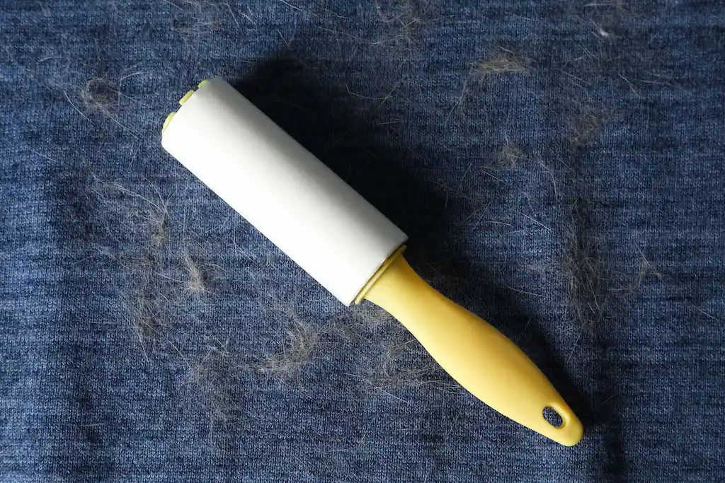 A lint roller on a blue fabric with pet hair