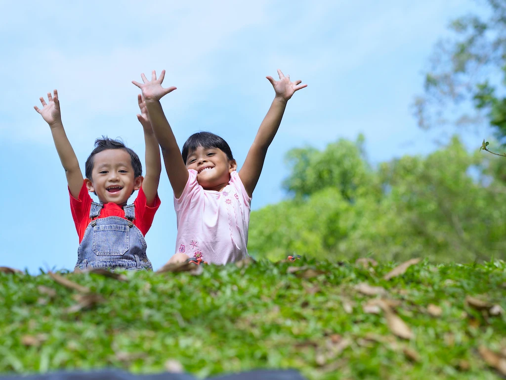Children raising hands outdoors, enjoying fresh air and a healthy environment