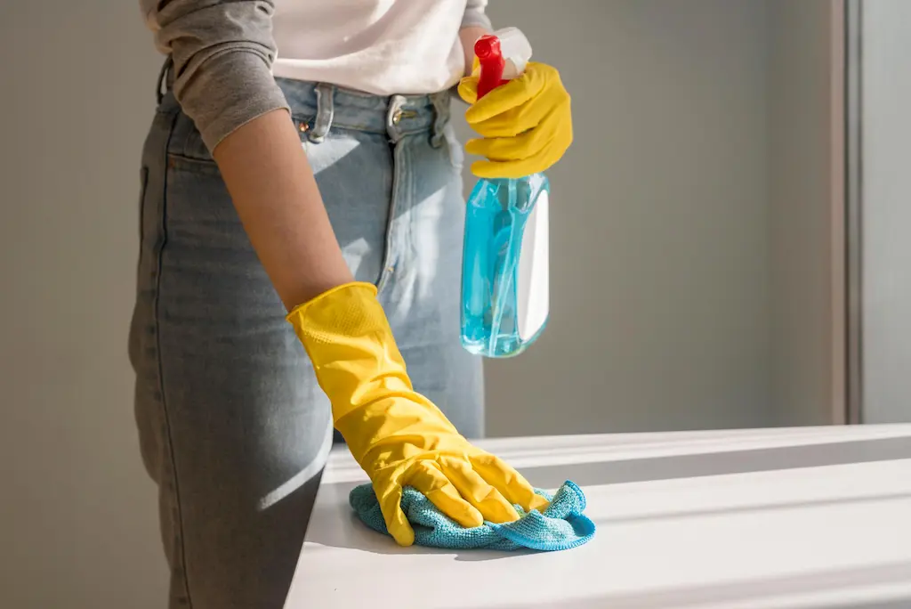 Hand in yellow gloves wiping countertop with cleaner - cleanfanatics