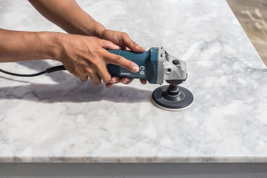 Person using a polishing machine on a marble surface.
