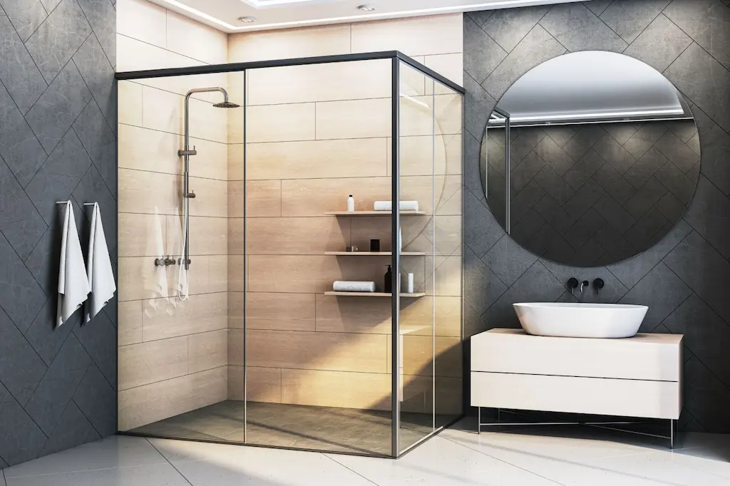 Modern bathroom with glass shower enclosure, round mirror, vessel sink, and black and wood finishes.